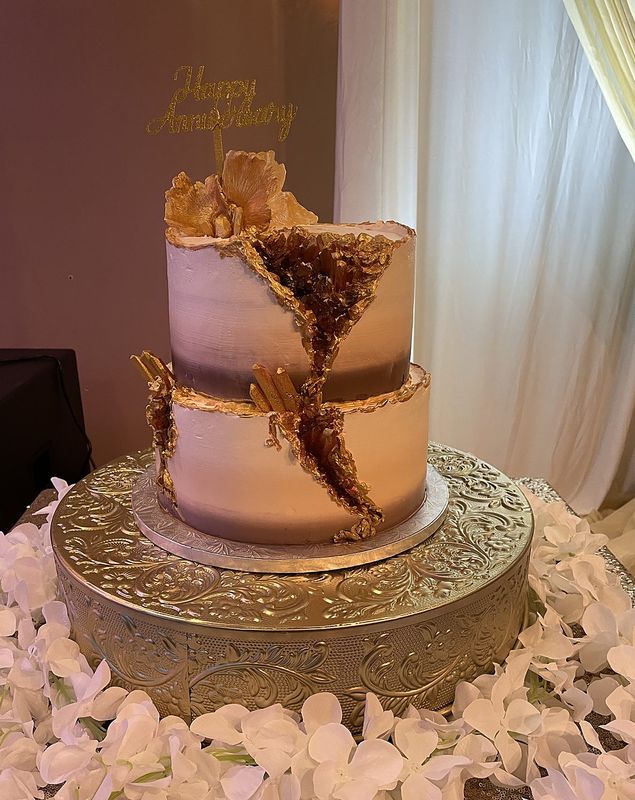 Two-tier blush and gold geode anniversary cake on a floral stand