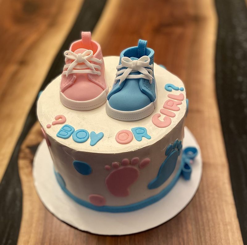 Gender reveal cake with pink and blue fondant baby sneakers