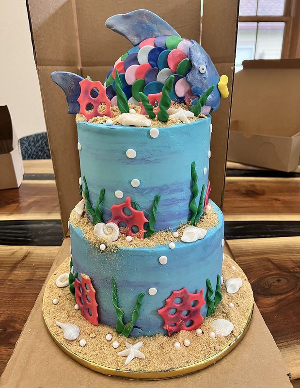 Two-tier ocean-themed birthday cake with coral, seaweed and a rainbow fish