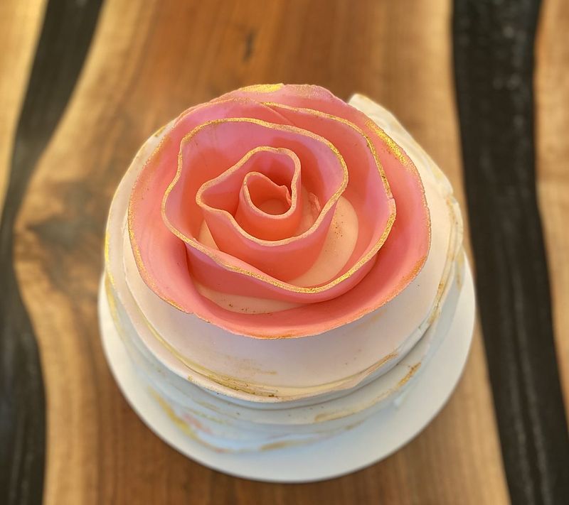 Small cake topped with one large sculpted coral sugar rose