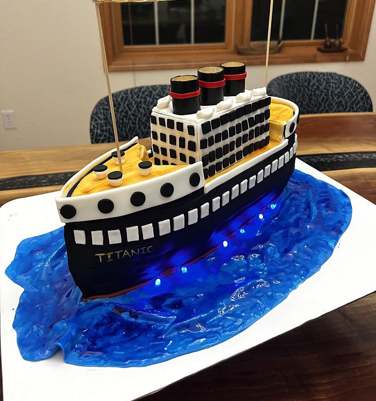 Sculpted ocean liner cake sailing on blue isomalt water with lights