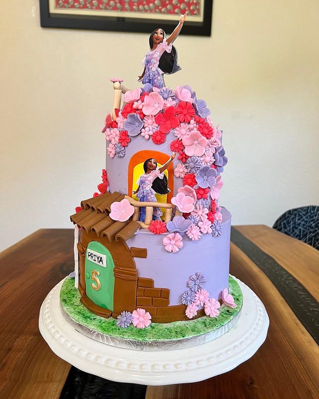 Whimsical fairytale cottage birthday cake covered in pink and purple sugar blossoms